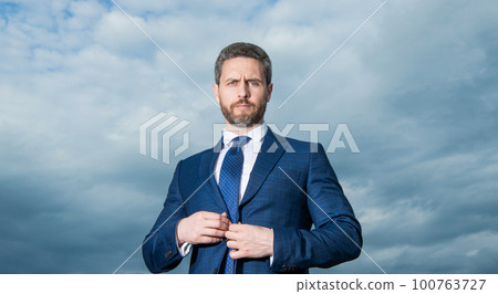 Portrait of man. Professional man buttoning suit. Grizzled man sky background Portrait of man. Professional man buttoning suit. Grizzled man sky background 100763727