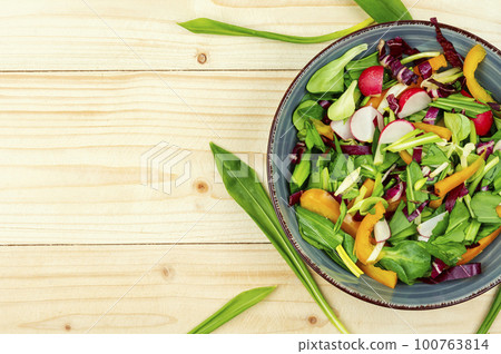 Salad with wild garlic on a rustic wooden board. Salad with wild garlic on a rustic wooden board. 100763814