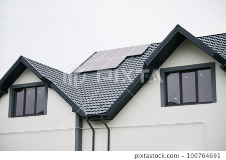 Bottom view of house with solar panels on roof. Photovoltaic solar system on modern house. Alternative energy resources in our life. Bottom view of house with solar panels on roof. Photovoltaic solar system on modern house. Alternative energy resources in our life. 100764691