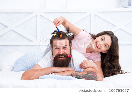 Pajamas party. Happy childhood. Upbringing happy daughter. Relaxing in bedroom. Family leisure concept. Girl dad hairdo. Quarantine with children. Affection and support. Happy family. Role of father 100765037