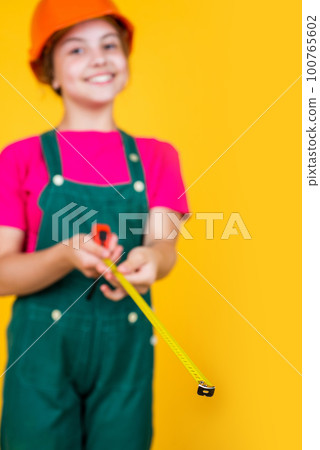 examining. kid wear helmet on construction site. teen girl builder with building tool tape measure. child on repairing work. concept of renovation in workshop. busy professional carpenter examining. kid wear helmet on construction site. teen girl builder with building tool tape measure. child on repairing work. concept of renovation in workshop. busy professional carpenter 100765602