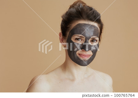 young female with cosmetic mask against beige background 100765764