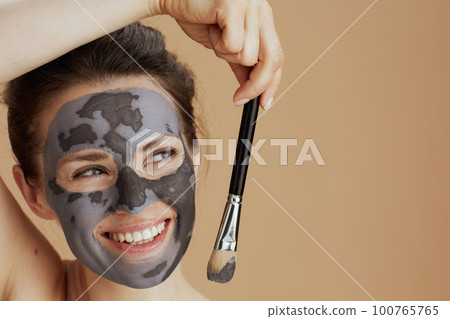 smiling modern 40 years old woman with brush and cosmetic mask 100765765