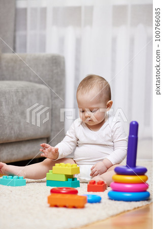 baby girl playing with colorful toy blocks 100766085