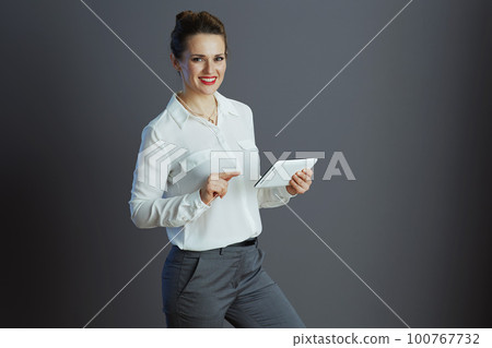smiling business owner woman using appt PC isolated on grey smiling business owner woman using appt PC isolated on grey 100767732