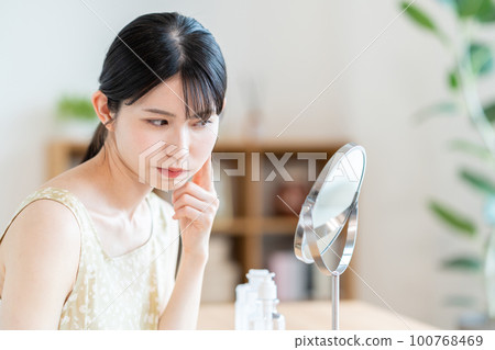 A middle-aged woman who checks the condition of her skin. 100768469