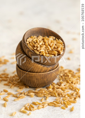 Wooden bowls of raw dry rye grain on white table close up 100768539