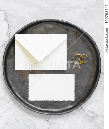 Black plate with a blank card, envelope and wto wedding rings top view, mockup Black plate with a blank card, envelope and wto wedding rings top view, mockup 100768545