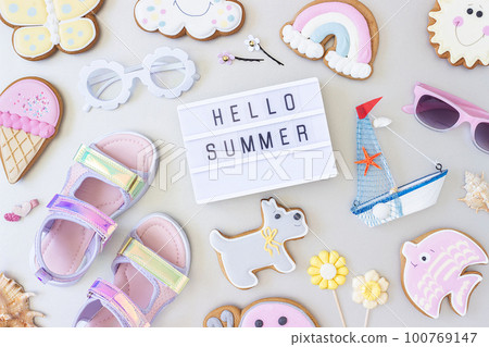 Hello summer text on lightbox and cute summer symbols on grey background. Top view, Flat lay. Creative summer concept, greeting card Hello summer text on lightbox and cute summer symbols on grey background. Top view, Flat lay. Creative summer concept, greeting card 100769147