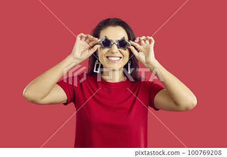 Funny woman in cool sunglasses on red studio background 100769208