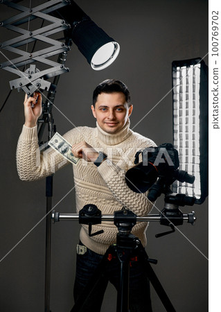 photographer with digital camera on tripod holding hundred dollar bills photographer with digital camera on tripod holding hundred dollar bills 100769702