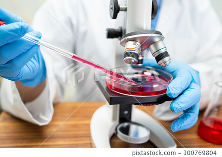 Scientist holding erlenmeyer flask, conical flask glassware with red color liquid solution in science chemistry laboratory. 100769804