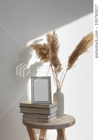 Wooden table with stack of books and vase with pampas grass, mock-up gray frame 100769817