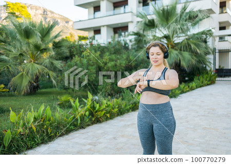Young plus size woman with smart watch. Girl training in park. Woman with fitness tracker. Copy space and empty space for text 100770279