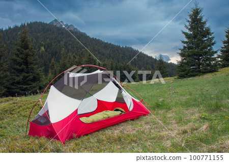 Sleepin bag in open inner tent body without rainfly, on mountain col in grass in the morning. On background Velky Rozsutec. Mala Fatra mountains, Slovakia. 100771155