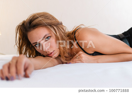 Fashion. Portrait of a Sexy blonde woman posing lying on the bed. Close up Fashion. Portrait of a Sexy blonde woman posing lying on the bed. Close up 100771888
