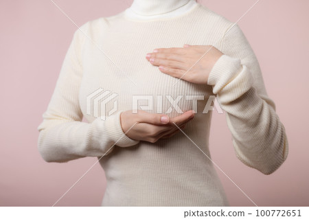 Woman hands checking lumps on her breast for signs of breast cancer on pink background. Healthcare world health day concept. Woman hands checking lumps on her breast for signs of breast cancer on pink background. Healthcare world health day concept. 100772651