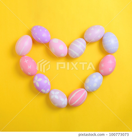 Happy easter holiday celebration concept. Group of painted colourful eggs in heart shape decoration on a yellow background. Seasonal religion tradition design. Top view, flat lay, copy space. 100773073