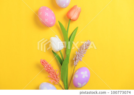 Happy Easter holiday greeting card design concept. Colorful Easter Eggs and spring flowers on yellow background. Flat lay, top view, copy space. 100773074