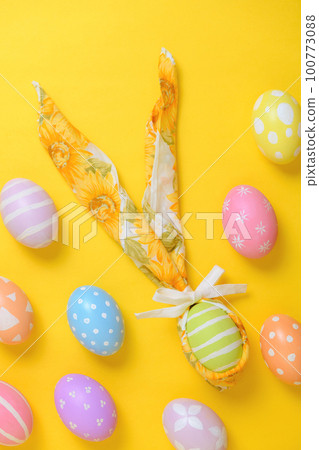 Colorful painted easter egg decorated with a napkin in the shape of a bunny on a yellow background 100773088