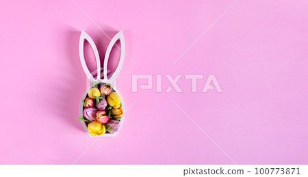 Wooden easter bunny statuette with spring tulips on the pink background, easter minimal concept, top view with copy space Wooden easter bunny statuette with spring tulips on the pink background, easter minimal concept, top view with copy space 100773871