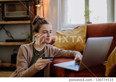 Young woman shopping online in her apartment. Young woman shopping online in her apartment. 100774514