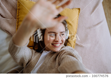 Top view of young woman listening music trough headphones. 100774576