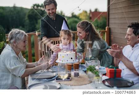Multi generation family celebrating birthday and have garden party outside in the backyard on patio. Multi generation family celebrating birthday and have garden party outside in the backyard on patio. 100774863