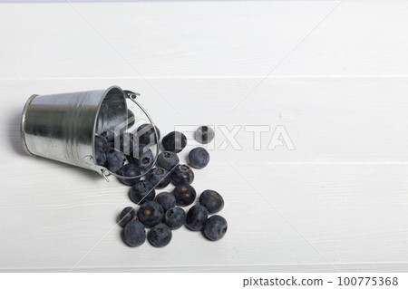 Overturned decorative bucket. Scattered large blueberries. International day without diets. On a white background. Close-up. 100775368