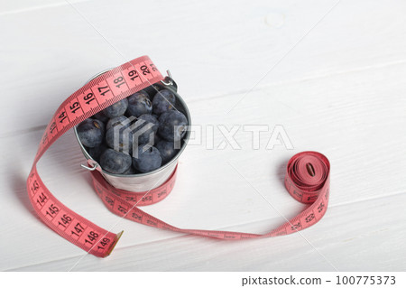 Large blueberries in a decorative bucket. International day without diets. On a white background. Close-up. 100775373