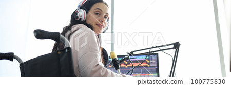 Female freelancer programmer or streamer in modern headphones sits in wheelchair and uses computer 100775830