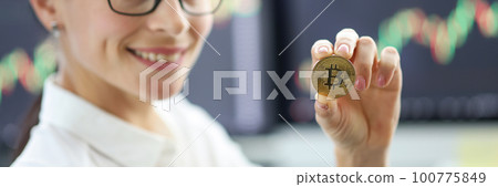 Portrait of smiling businesswoman in glasses holding golden bitcoin Portrait of smiling businesswoman in glasses holding golden bitcoin 100775849