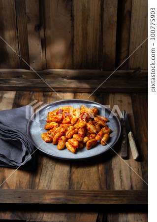 Italian potato Gnocchi with tomato sauce. Rustic style, wooden background Italian potato Gnocchi with tomato sauce. Rustic style, wooden background 100775903