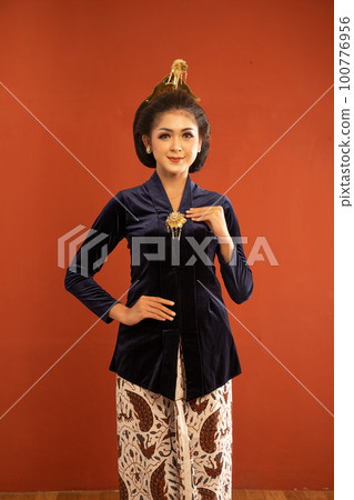 javanese woman in navy kebaya standing with smile while touch her kebaya 100776956