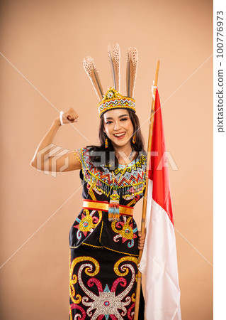 asian woman in one set of dayak traditional clothes standing with smile and clenched arm asian woman in one set of dayak traditional clothes standing with smile and clenched arm 100776973