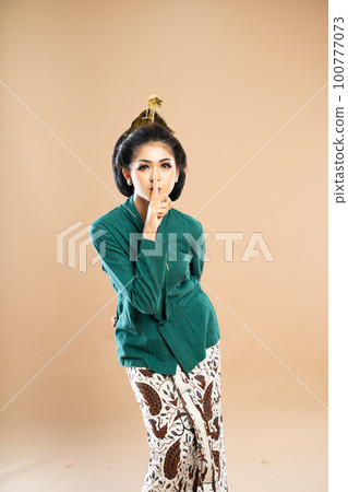 asian woman in green kebaya standing closing her mouth with her finger asian woman in green kebaya standing closing her mouth with her finger 100777073