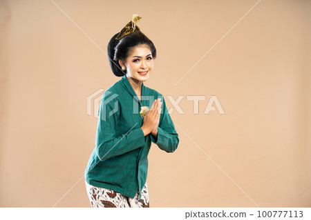 beautiful woman in green kebaya standing bent over with hands put together 100777113