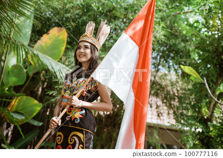 beautiful woman in traditional clothes standing and holding the indonesian flag beautiful woman in traditional clothes standing and holding the indonesian flag 100777116