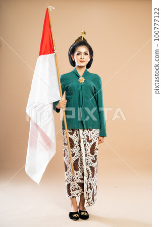 asian woman in green kebaya standing bring the Indonesian flag 100777122
