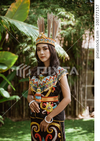 asian woman in traditional clothes of dayak tribe standing with solemn face 100777157