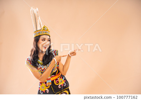 asian woman in king bibinge looking and pointing on her left side 100777162