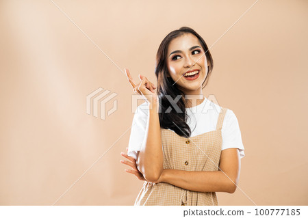 woman in casual clothes standing with smile while looking and pointing up 100777185