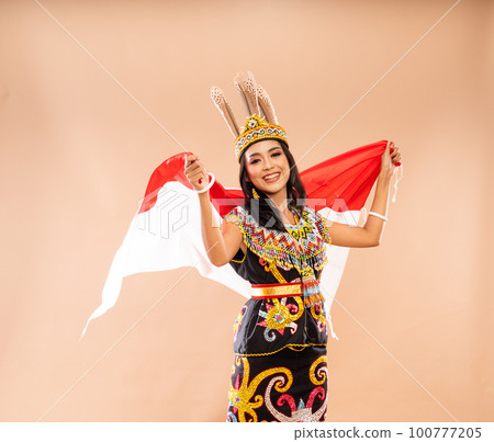 woman in traditional clothes of dayak tribe grab and waving the flag woman in traditional clothes of dayak tribe grab and waving the flag 100777205