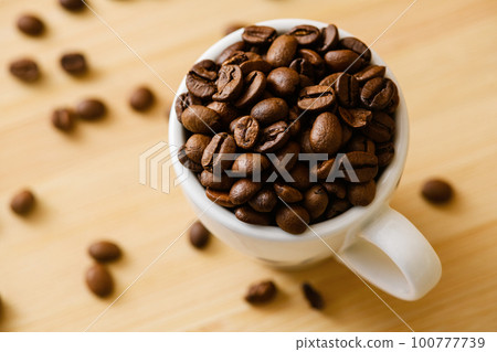 Cup full of coffee beans on table Cup full of coffee beans on table 100777739