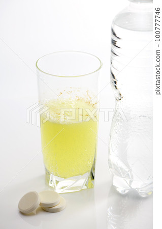 The effervescent tablet dissolves in a glass of water. 100777746