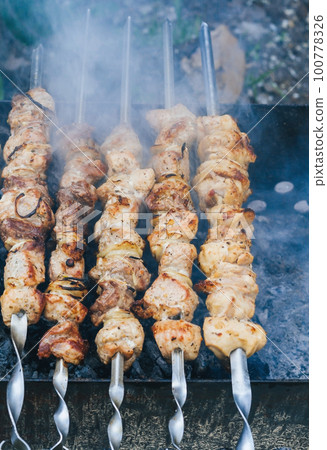Cooking meat on the fire top view, shish kebab on skewers, smoke on the grill Cooking meat on the fire top view, shish kebab on skewers, smoke on the grill 100778326