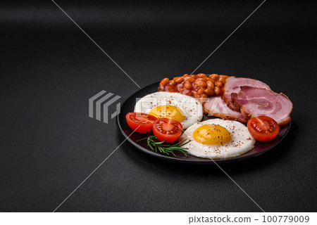 Delicious nutritious English breakfast with fried eggs and tomatoes Delicious nutritious English breakfast with fried eggs and tomatoes 100779009