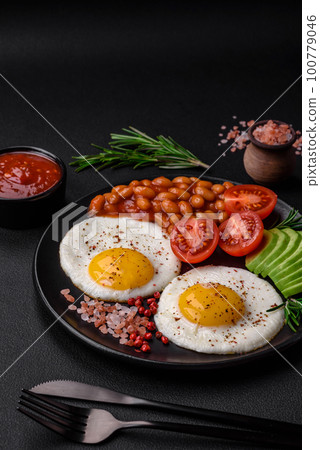 Delicious nutritious English breakfast with fried eggs, tomatoes and avocado 100779046