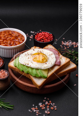 Delicious nutritious English breakfast with fried eggs, tomatoes and avocado Delicious nutritious English breakfast with fried eggs, tomatoes and avocado 100779059