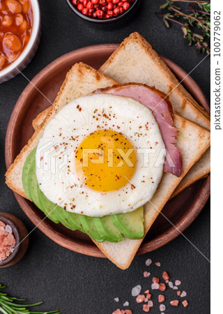 Delicious nutritious English breakfast with fried eggs, tomatoes and avocado 100779062